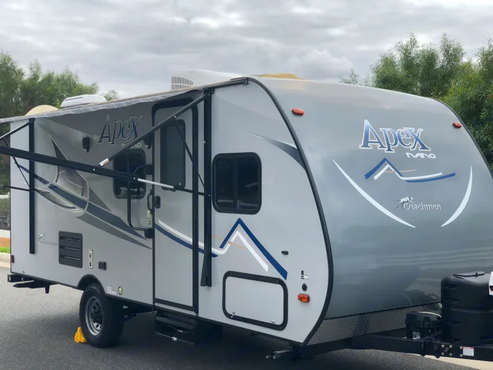 This gray Coachmen Apex Nano travel trailer, ready for your RV rental adventure, features an extended awning.. Coachmen Apex 2018