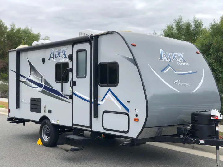 Compact Apex Nano travel trailer, ideal for your next RV rental adventure. This gray recreational vehicle is parked on asphalt.. Coachmen Apex 2018