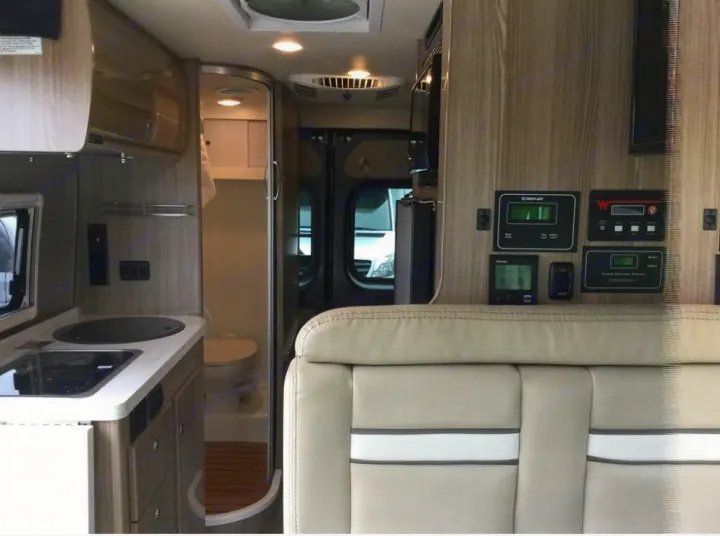 Inside a modern RV rental: a smart layout featuring kitchen, compact bathroom, and essential control panels.. Winnebago Travato 2019