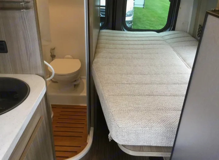 RV rental interior: compact bathroom with toilet, adjacent sink counter, and comfortable sleeping bed.. Winnebago Travato 2019