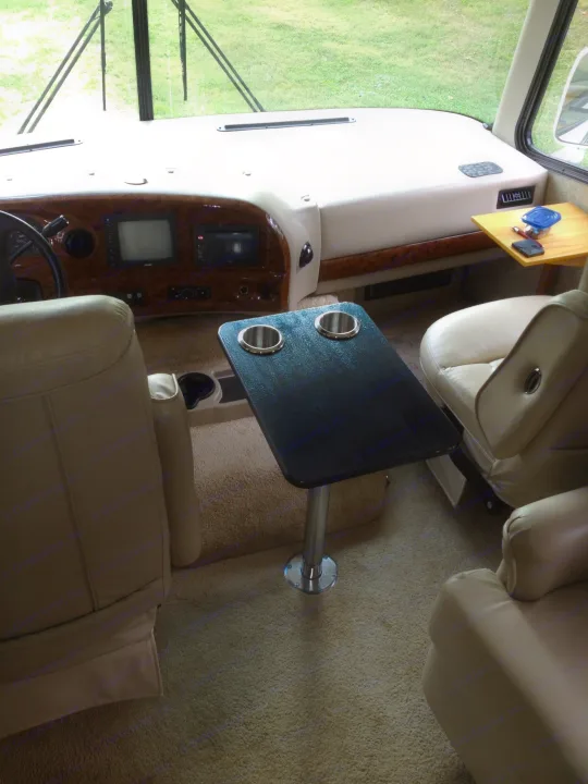 View of an RV rental's spacious cockpit area, featuring a dashboard, swiveling captain's chairs, and built-in tables.. Thor Motor Coach Hurricane 34N 2006