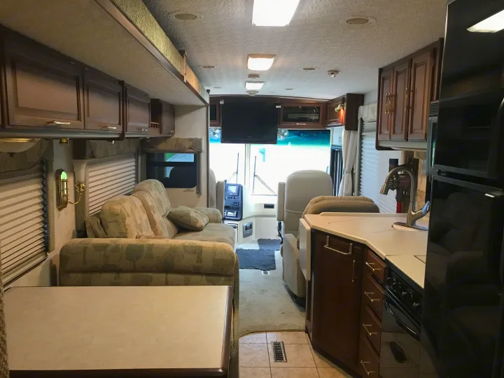 An RV rental's inviting interior features a cozy living space, equipped kitchen, and driver's cockpit.. Winnebago Journey 2004