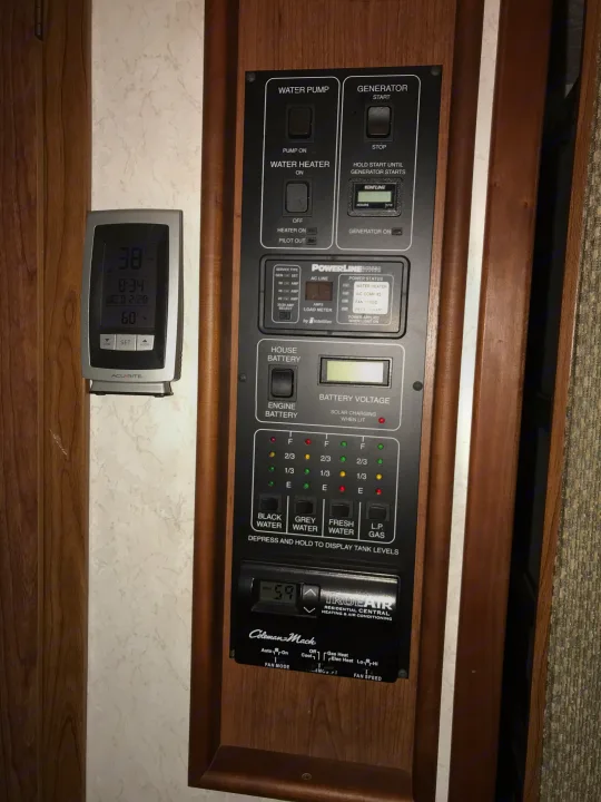 RV rental interior control panel displaying generator, water, power, battery, tank levels, & climate controls.. Winnebago Journey 2004