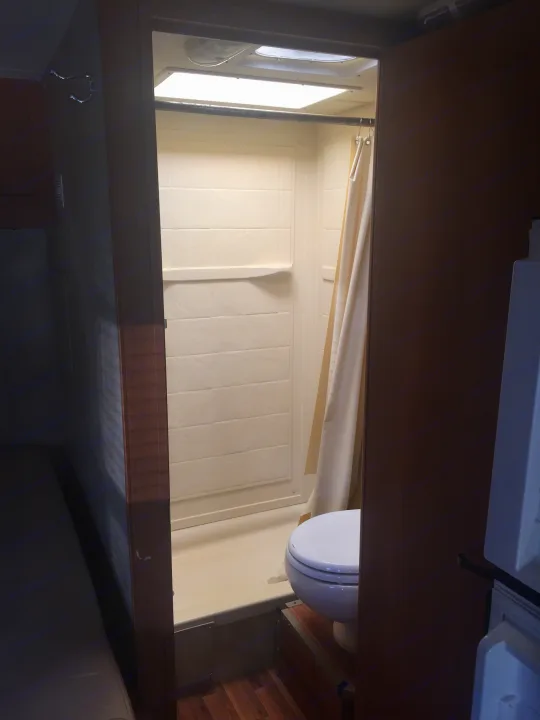 Inside an RV rental: a bright, compact wet bath featuring a shower, toilet, and window.. Ford Majestic 23A 2012