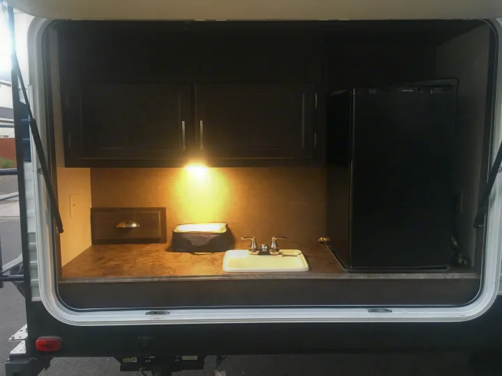 Perfect for an RV rental adventure! This outdoor kitchen has a sink, cabinets, light, and compact refrigerator.. Forest River Evo 2016