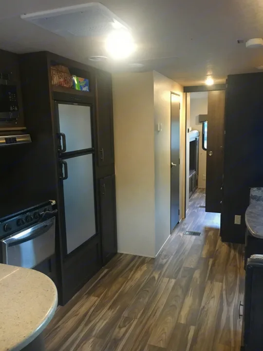 RV rental interior showing a well-equipped kitchen with appliances and a clear hallway with wood-look flooring.. Forest River Evo 2016