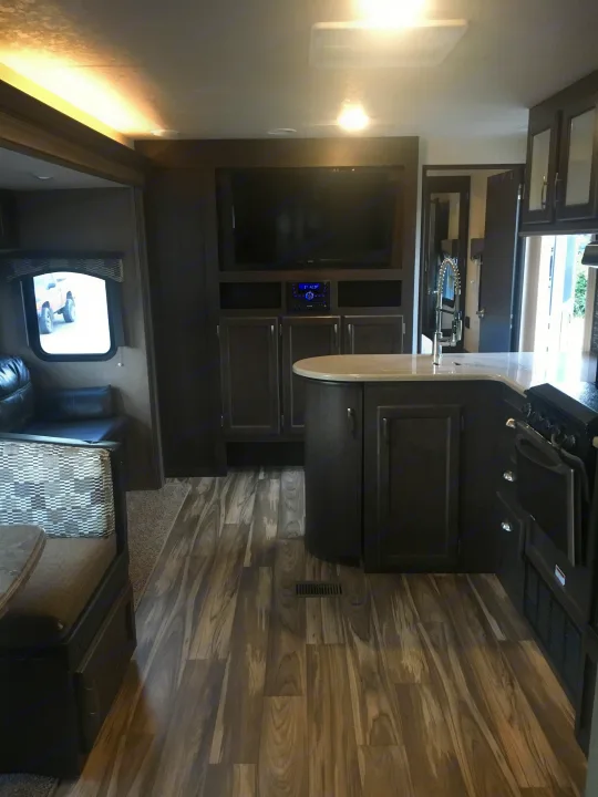 Modern RV rental interior showcasing a full kitchen, entertainment center, and cozy living space with wood flooring.. Forest River Evo 2016