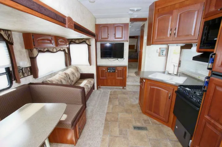 Spacious RV rental interior with a dinette, sofa, TV, and a well-equipped kitchen.. Keystone Cougar 280BHS 2015