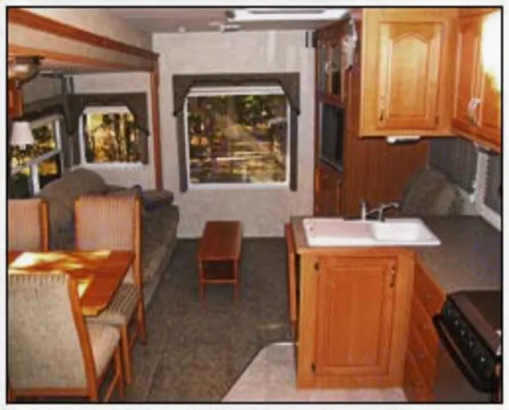 This RV rental interior features a cozy living space with a dining table, couch, and compact kitchen area.. Citation Supreme 29CKS 2012