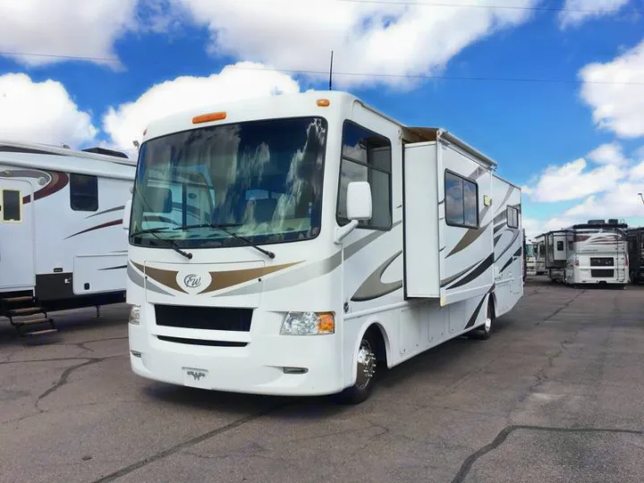 White motorhome with extended slide-out, ready for an RV rental adventure. Parked on asphalt under a blue sky.. Ford Hurricane 2011