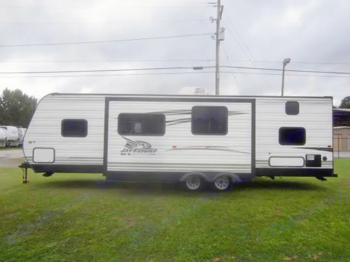 White Jay Flight SLX travel trailer RV for rental, parked on green grass under cloudy sky.. Jay Flight 287 BHSW 2016
