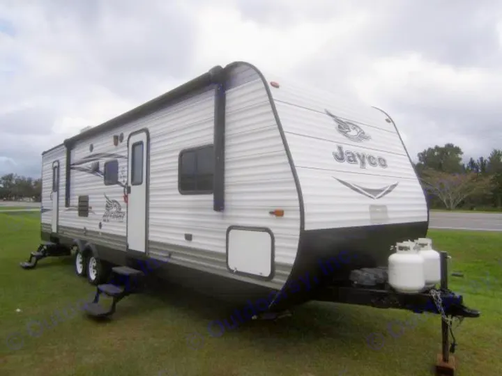 White Jayco travel trailer, an ideal rv rental option, parked on green grass under a cloudy sky. Explore in comfort.. Jay Flight 287 BHSW 2016