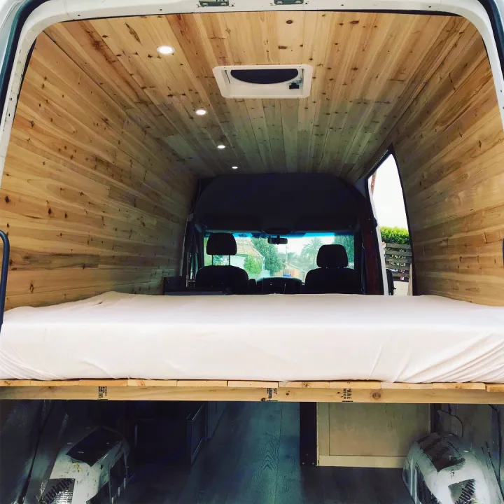 Cozy RV rental: Inside a wood-paneled camper van with a built-in bed. Perfect for your next mobile adventure!. Dodge Sprinter Van 2007