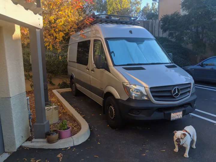 Silver Mercedes Sprinter van RV rental, parked with a bulldog. Ideal for pet-friendly travel adventures.. Mercedes-Benz Sprinter 2016