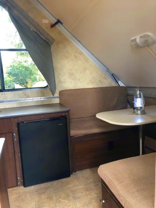 RV rental: A-frame camper interior with dinette, Haier fridge, and natural light from the window.. A-Liner Scout 2013