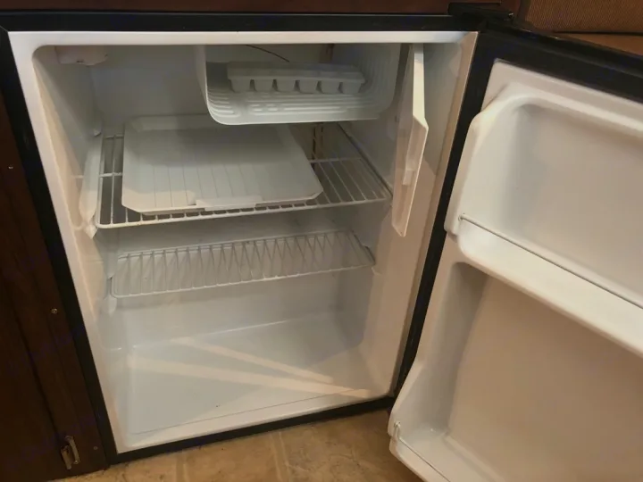 An open, clean mini-refrigerator inside an RV rental, featuring an ice tray and shelves, ready for your journey.. A-Liner Scout 2013