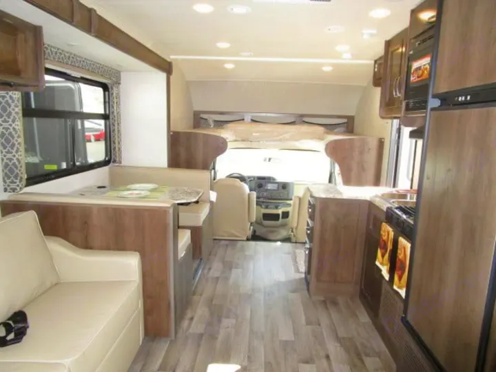 Spacious rv rental interior showing kitchen, dinette, and living area with light wood-look flooring.. Jayco Redhawk 2019