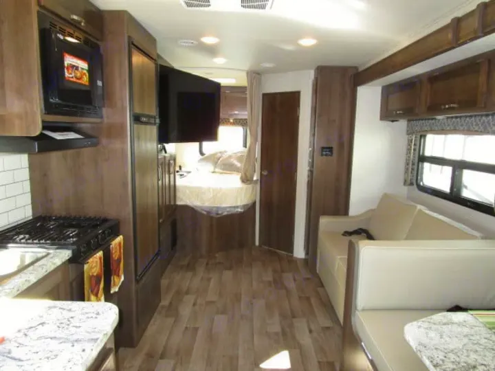 Discover this RV rental's spacious interior: full kitchen, sofa-equipped living area, and a private bed at the rear.. Jayco Redhawk 2019