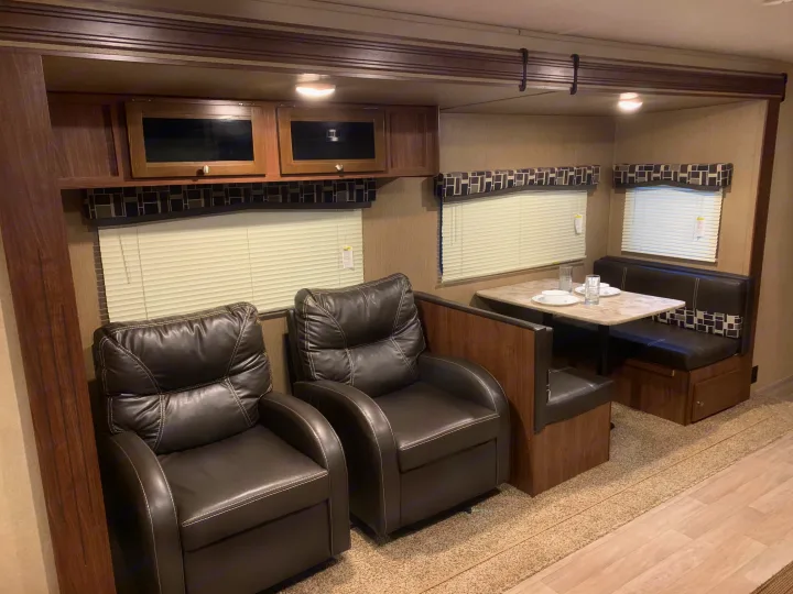 Cozy RV rental interior with recliners, a dining booth, and overhead storage. Ideal for comfortable travel.. Coleman Lantern 2018