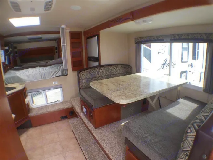 Spacious RV rental interior featuring a comfortable bed, dinette area, and compact kitchen.. Adventurer F350 2006