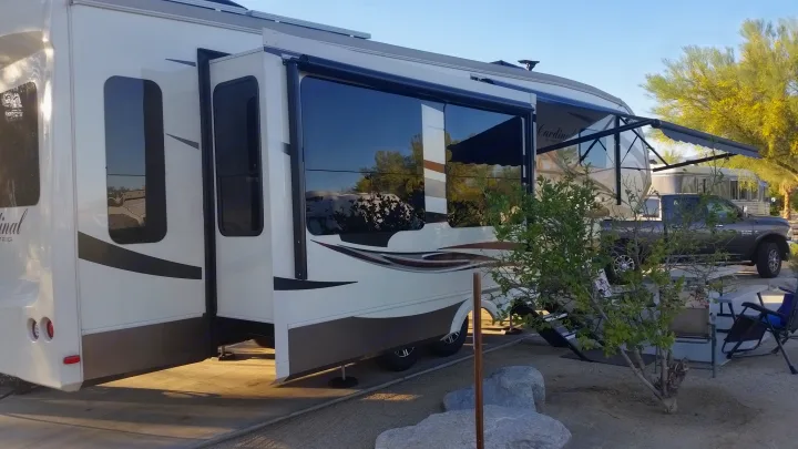 Spacious RV rental fifth wheel with slide-outs and awning at a sunny campsite, truck parked nearby for travel.. Forest River Cardinal 2017