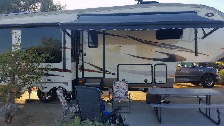 Enjoying an RV rental! A large fifth-wheel with its awning extended, a picnic table, and chairs for outdoor relaxation.. Forest River Cardinal 2017
