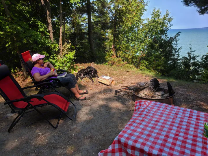 Relaxing at a scenic lakefront campsite, a perfect stop for your rv rental adventure. Enjoying nature with a good book and a loyal dog by the fire pit.. United XLMTV-610 2018