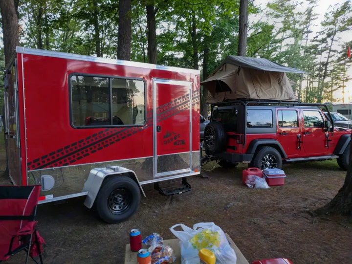 Red RV rental trailer & Jeep with rooftop tent set up for camping. Ideal for rugged outdoor excursions.. United XLMTV-610 2018