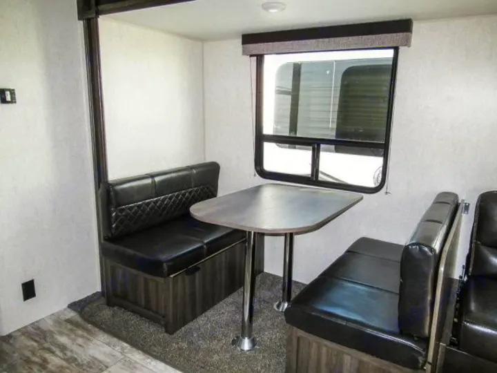 Cozy RV rental dinette featuring black upholstered benches, a table, and a large window, perfect for dining.. Openrange 26BHS 2020
