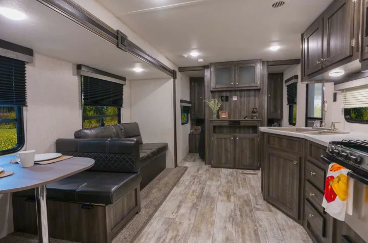 Spacious RV rental interior featuring a modern dinette, sofa living area, and full kitchen.. Openrange 26BHS 2020