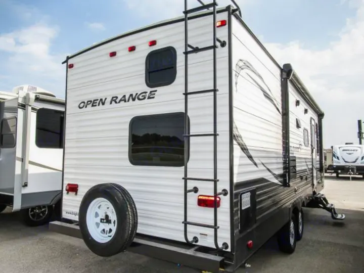 Rear view of a white "OPEN RANGE" travel trailer with a ladder and spare tire. Perfect for your next RV rental.. Openrange 26BHS 2020