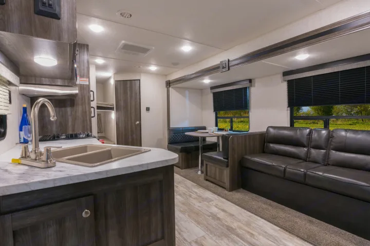 Explore this comfy **rv rental** interior with a well-equipped kitchen area, cozy dinette, and spacious living room sofa.. Openrange 26BHS 2020
