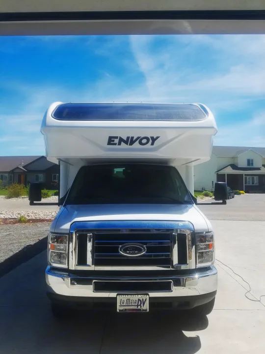 A white Ford Class C RV, model Envoy, from La Mesa RV for rv rental, parked head-on under a sunny sky.. Jayco Envoy 2018