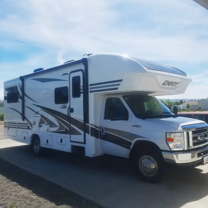 Spacious white & gray Envoy Class C motorhome for rv rental, parked on concrete under a blue sky, ideal for trips.. Jayco Envoy 2018