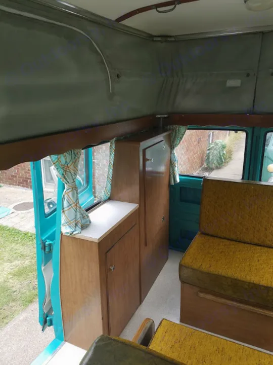 Explore our vintage camper van RV rental! Cozy interior with pop-top roof, wooden cabinets, and comfy seating for your road trip.. Dodge A-108 Sportsman CampWagon 1967