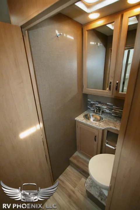 Compact RV rental bathroom: sink, vanity, toilet, and mirror. Perfect for travel convenience.. Thor Motor Coach Four Winds 2019
