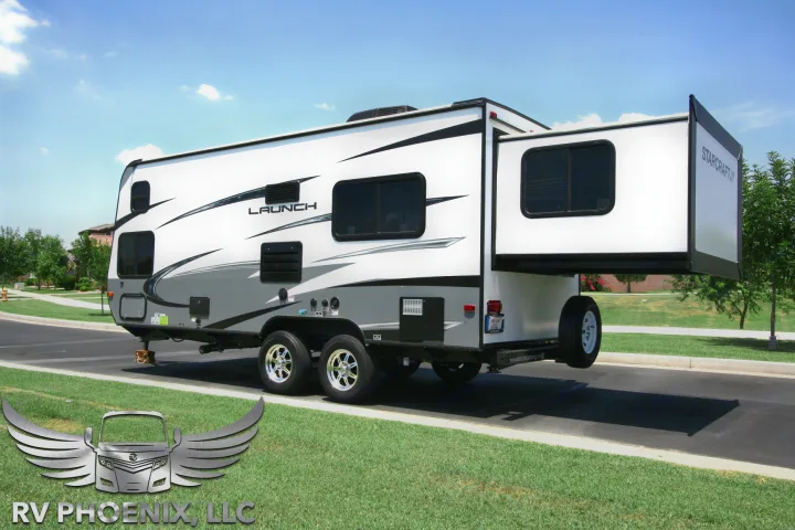 White & grey Starcraft Launch travel trailer (RV) with extended slide-out, parked outdoors. Ideal for RV rental.. Starcraft Launch 19BHS 2017