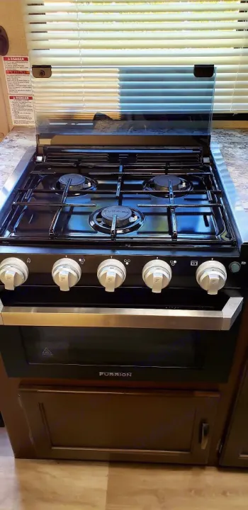 Sleek Furrion stove and oven combo in an RV rental, featuring 3 burners. Ideal for compact RV kitchen cooking.. Thor Motor Coach Freedom Elite 22 HEF 2019