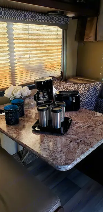Cozy RV rental dinette with granite-look table, coffee maker, toaster, and pleated blinds.. Thor Motor Coach Freedom elite 23 H 2019