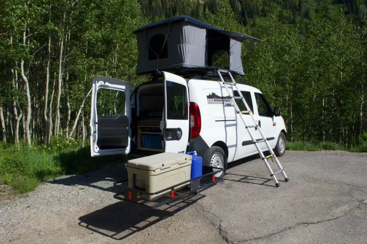 White compact RV rental camper van with rooftop tent & gear for off-grid camping in nature.. Ram Promaster City 2018