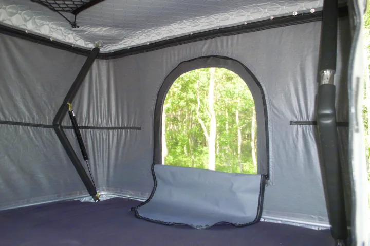 RV rental interior shows a cozy sleeping area with a scenic arched window and mosquito net, perfect for nature views.. Ram Promaster City 2018