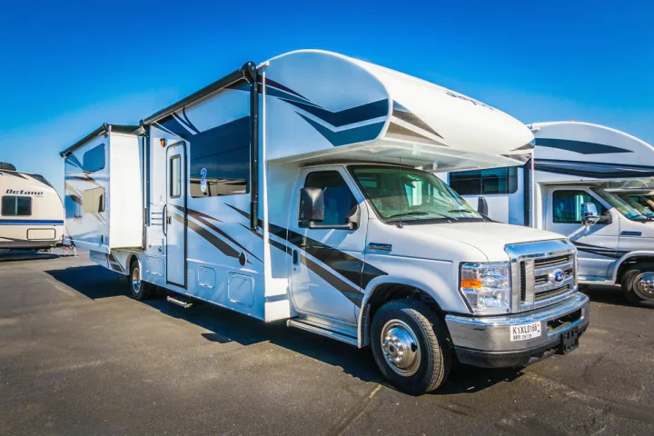 A white Class C RV motorhome, perfect for rv rental, parked on asphalt with its slide-out extended.. Jayco Redhawk 31 XL 2019