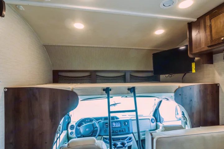 Experience the spacious interior of this RV rental, featuring an overhead bunk bed, TV, and ladder for easy access to the sleeping area.. Jayco Redhawk 31 XL 2019