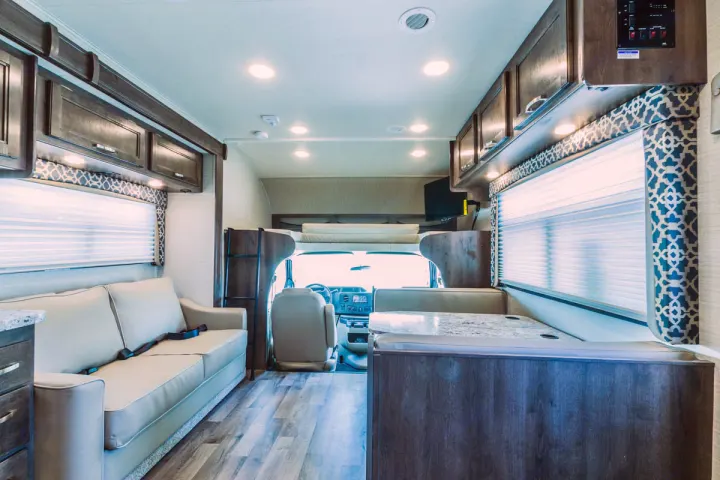 Spacious RV rental interior with modern decor, comfy sofa, dinette, and driver's cab visible.. Jayco Redhawk 31 XL 2019