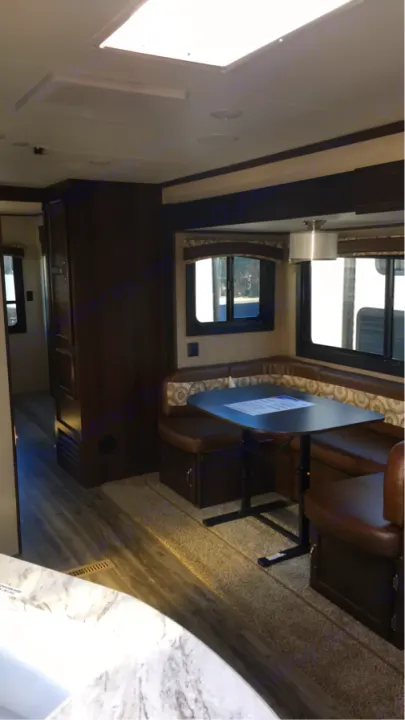 RV rental interior with a spacious U-shaped dinette, brown seating, and table. Features include large windows and mixed flooring.. Jayco Flight 2018