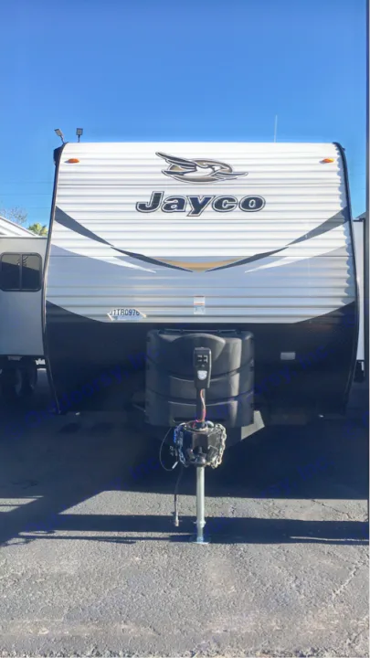Front view of a Jayco travel trailer, an excellent RV rental option, parked on asphalt under a clear blue sky.. Jayco Flight 2018
