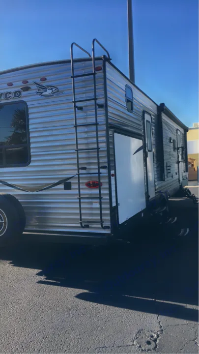 This shiny silver Jayco RV rental, a travel trailer, features a rear ladder and is parked outdoors under a sunny blue sky.. Jayco Flight 2018