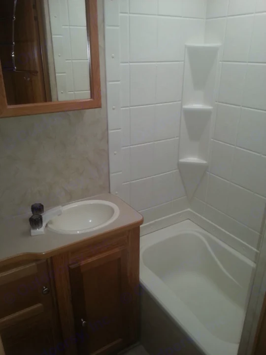 Clean RV rental bathroom featuring a sink, wooden vanity, and compact tub/shower combo with white tile walls.. R-Vision TS 24BH 2011