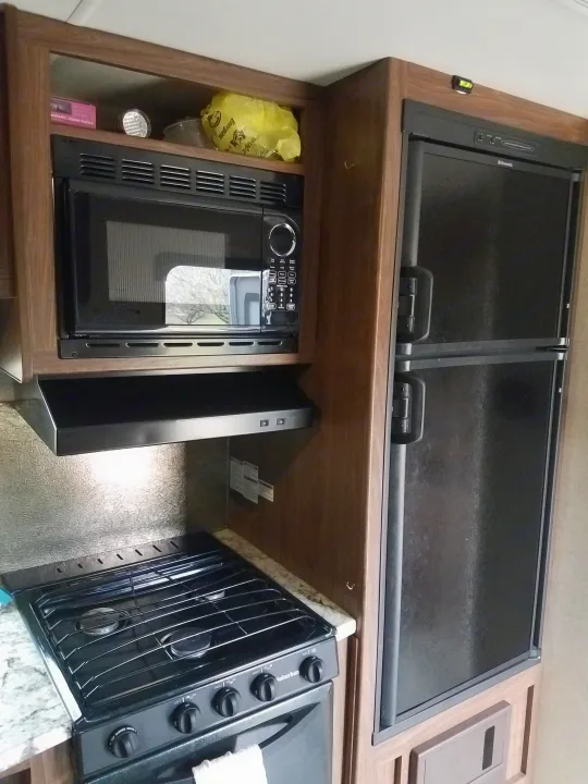 RV rental kitchen with microwave, range hood, gas stove, oven, and refrigerator.. Heartland Pioneer 2016