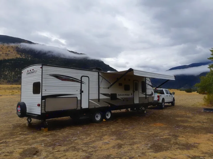 Spacious rv rental travel trailer & truck parked in a scenic, cloudy mountain landscape, ready for outdoor adventure.. Starcraft Autumn Ridge 2018